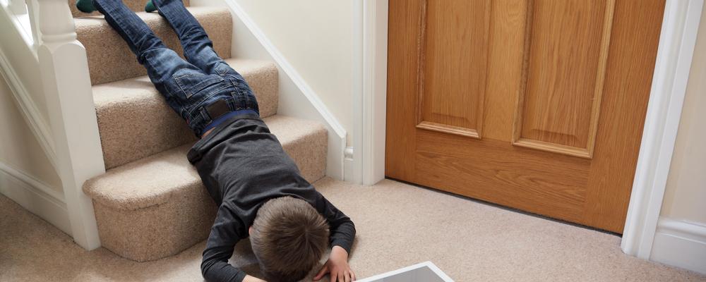 Boy falling down the stairs face forward with tablet on the floor