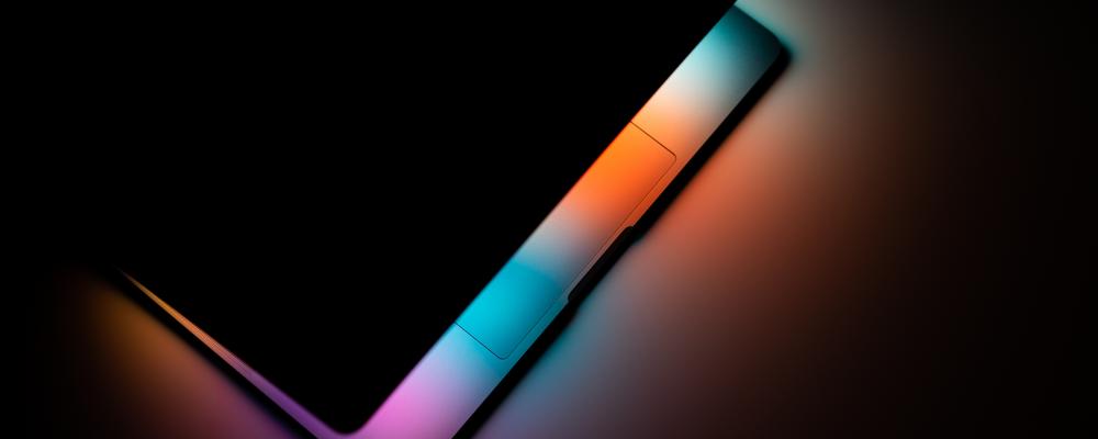Macbook pro - färgglada ljus från skärmen lyser upp ett bord. 