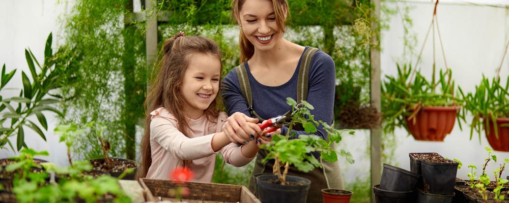 Mother and daughter growing plants in greenhouse