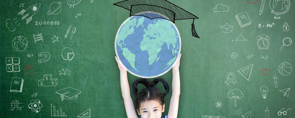 School girl kid raising world globe and graduation cap doodle on green chalkboard