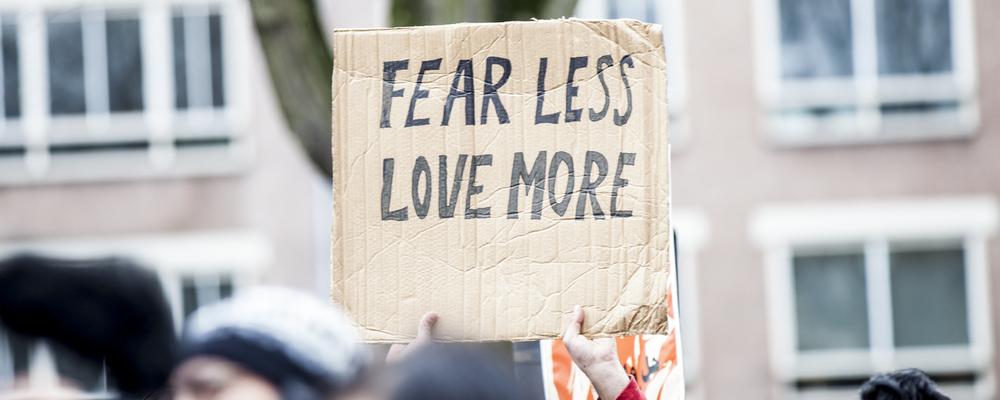 Demonstrationsskylt med budskapet Fear less, love more