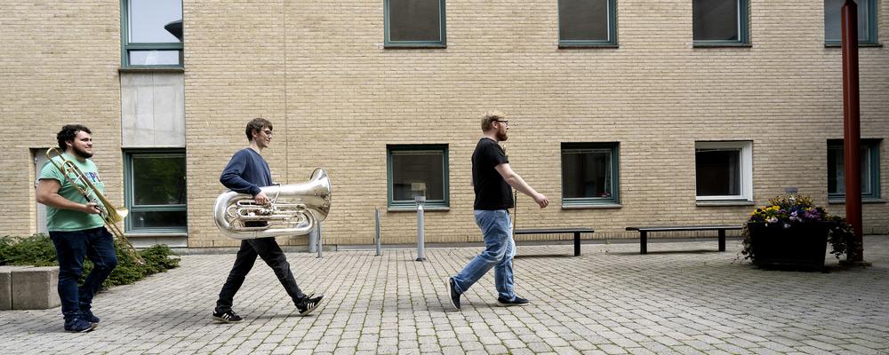 Tre personer med brassinstrument går utanför Eklandagatan 86