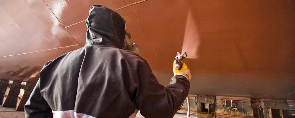 Person med skyddskläder målar fartyggskorv