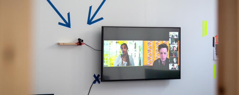 En TV-skärm på en ljus vägg med blåa pilar som pekar nedåt