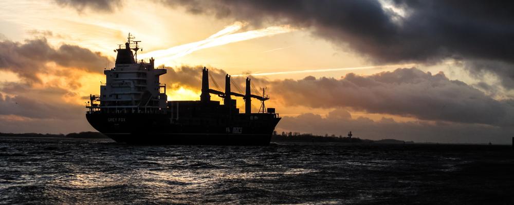 Ett fraktfartyg i solnedgången i ett hav.