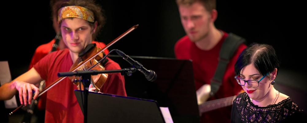 Three persons play different musical instruments
