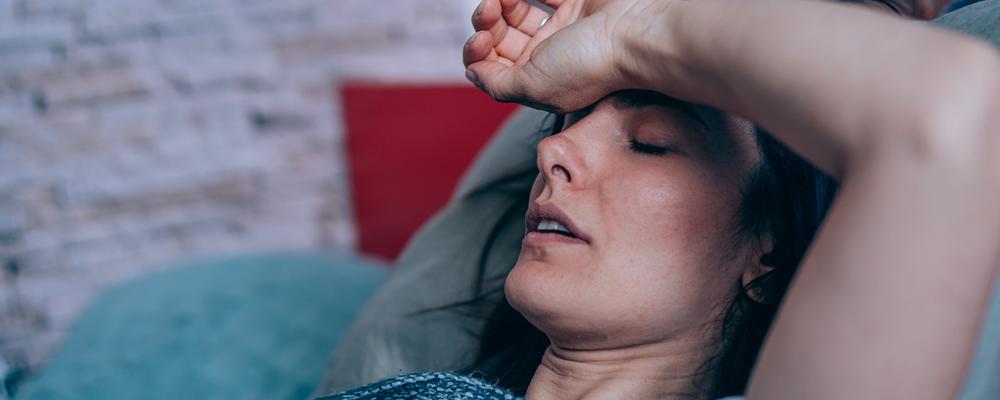 Kvinna ligger sjuk i sängen