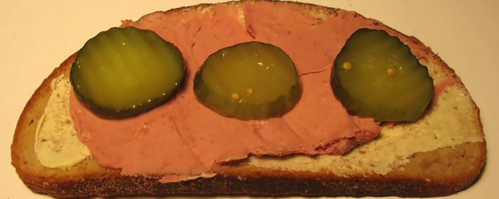 A sandwich with liver paste and pickled cucumber slices