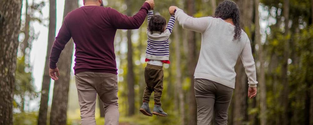 Couple with child walking in beautiful green forest