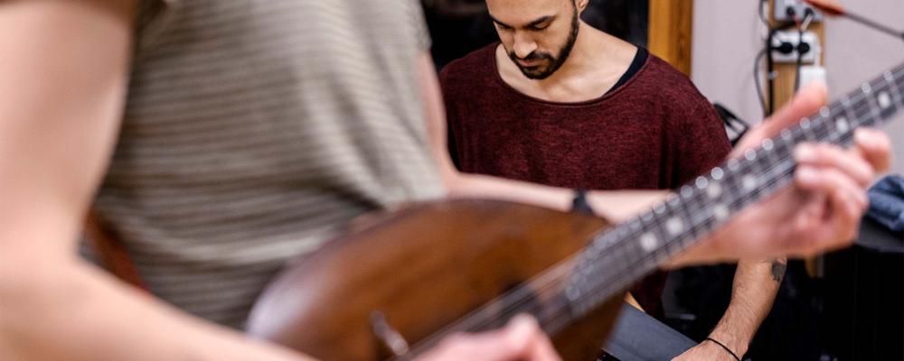 A person with a string instrument, another in the background