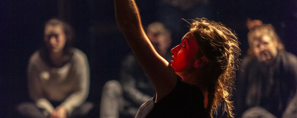 A person dances before a group of persons