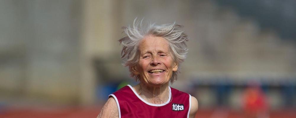 Bild på äldre kvinna i Sverigetröja som stöter kula