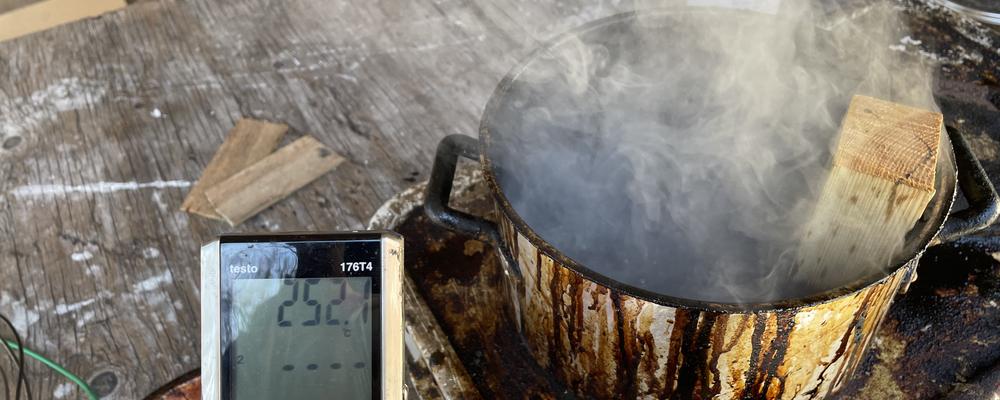 Bilden visar en gryta m,ed kokande tjära och i förgrunden en digital termometer.