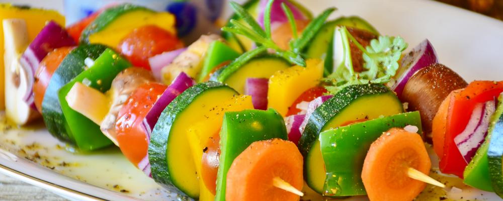 Tre grillspett med grönskaker på en tallrik