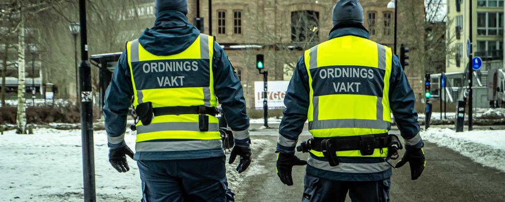 Två ordningsvakter som promenerar i stadsmiljö