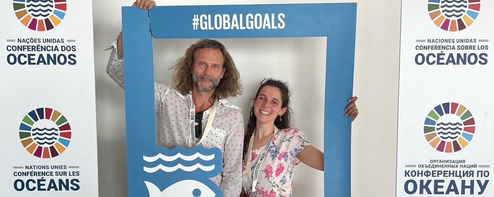Two people attending the UN Ocean Conference holding global goals.