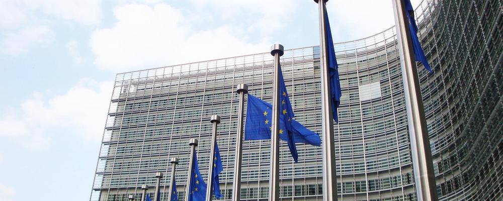 Foto av EU-byggnad i Bryssel med EU-flaggor hängande utanför entrén