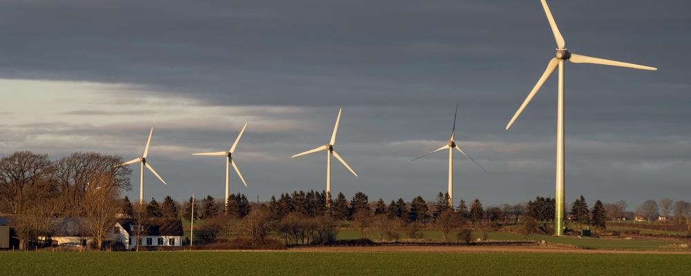 Foto av vindkraftverk på österlen nära hus på landsbygden