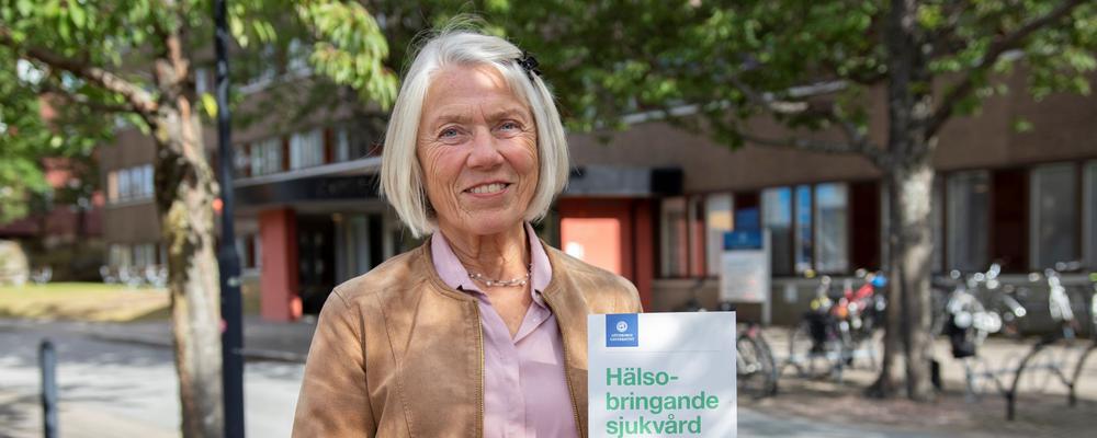 Foto på forskaren Marianne Törner som visar upp sin bok Hälsobringande sjukvård - för personal och patienter