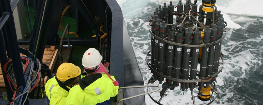 Researcher bringing a measuring instrument on board in the Arctic