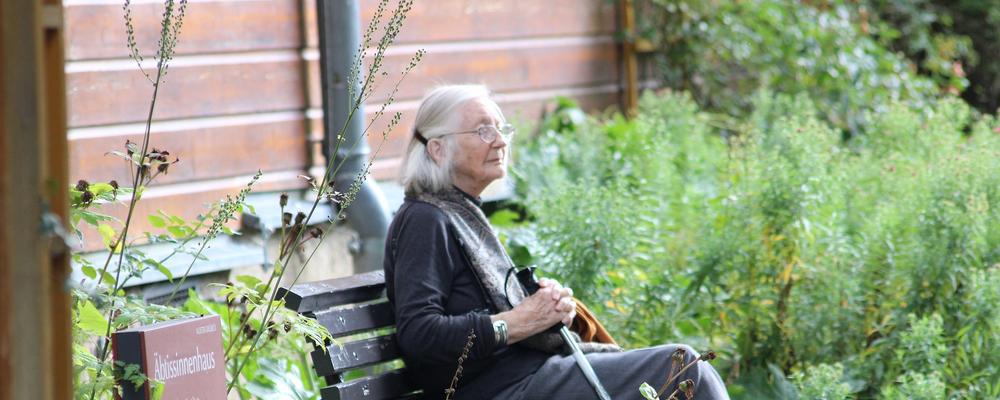 äldre kvinna sitter i trädgård till äldreboende