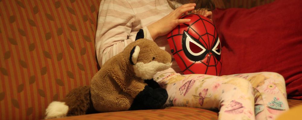 Ett barn sitter i en soffa och håller i en leksak