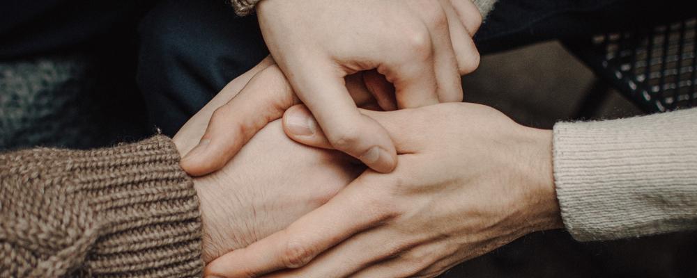Foto av händer som håller om varandra i samband med seans eller healing eller liknande