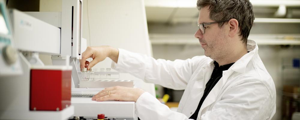 En forskare står i ett labb iklädd vit rock. 
