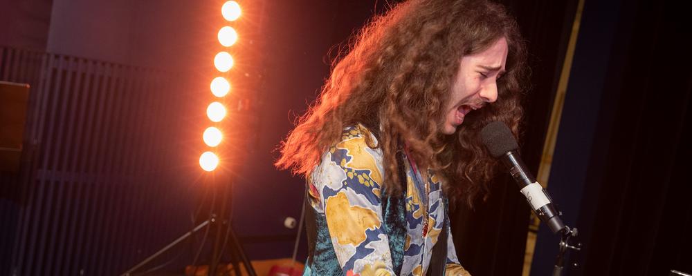 Ung musiker vid flygeln sjunger med passion.