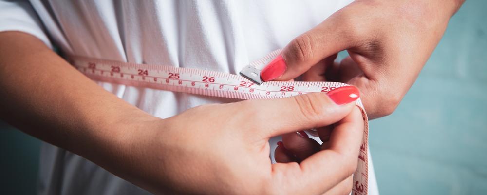 Kvinna som mäter midjan med ett måttband