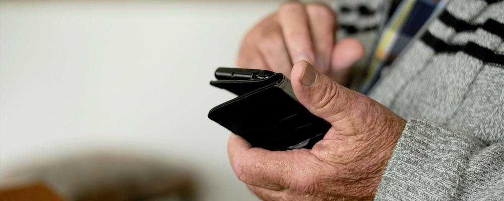 En äldre person håller i en mobiltelefon