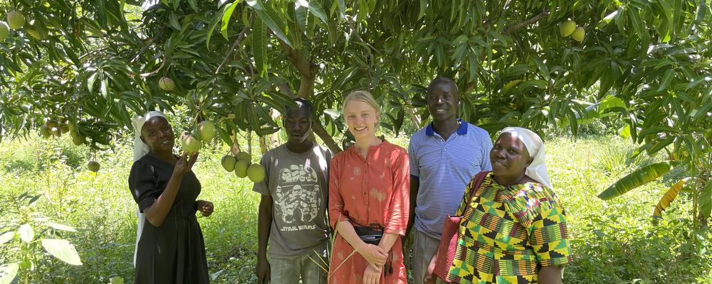 En grupp människor står framför grönskande område i Afrika.