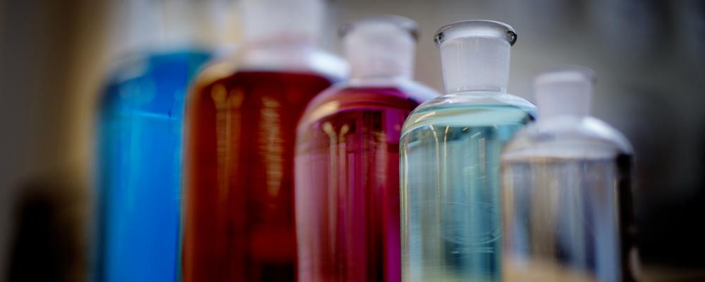 Bilder på glasflaskor med färgade vätskor.