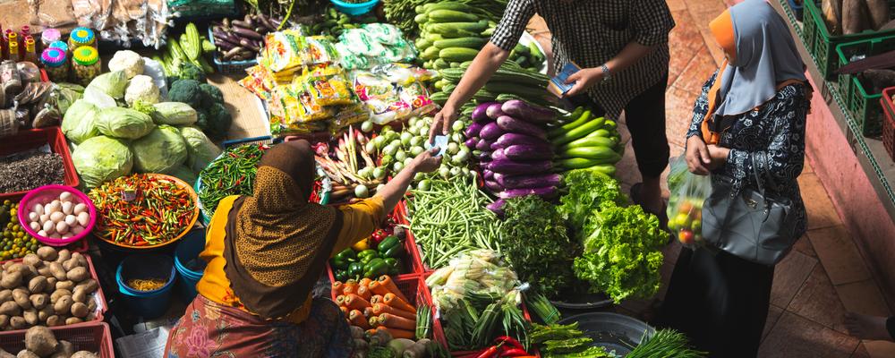 Människor handlar grönsaker på en marknad.