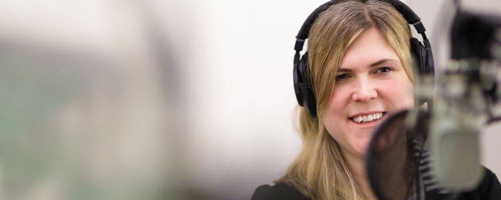 Maria Hoff med lurar på framför mikrofonen i inspelningsstudion. Hon ser glad ut.