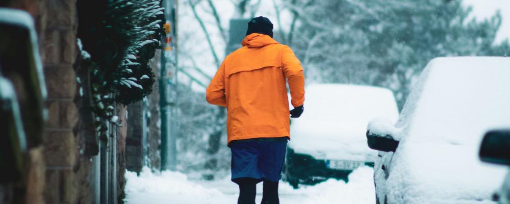 Man som springer på snöig gata