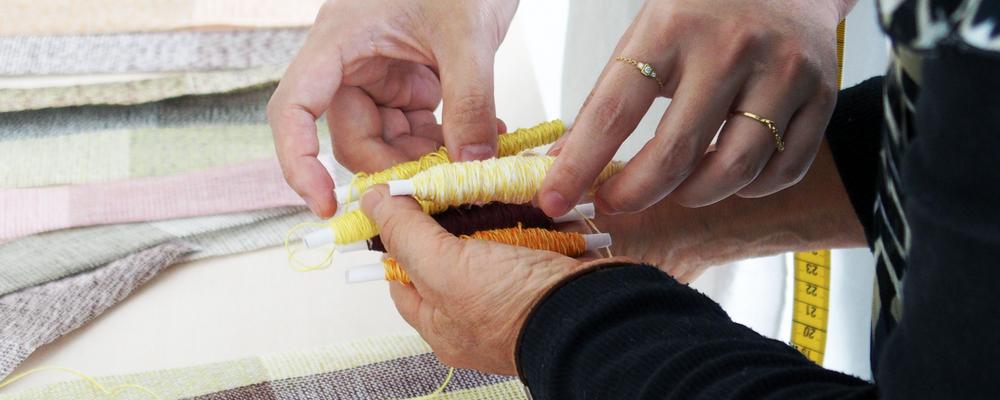 händer som arbetar med textil och tråd