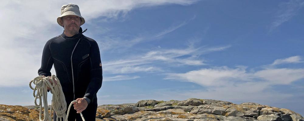 En man står och håller i en båt.