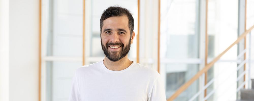 Vitor standing in the School hallway smiling and wearing a white tshirt. 