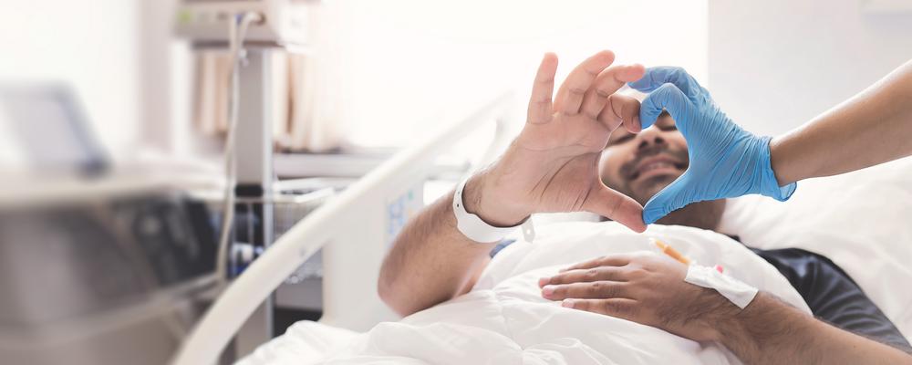 En man i en sjukhussäng - rummet ljust och luftigt