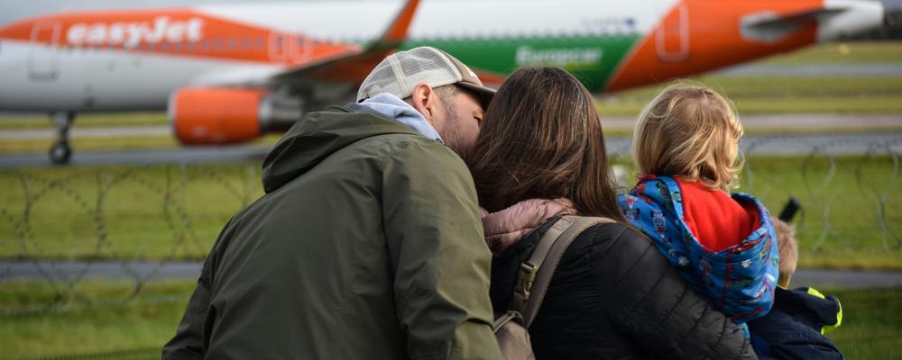 Familj står tillsammans och tittar på ett flygplan.