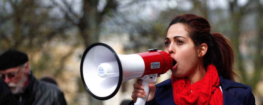 Kvinna ropar i en megafon under en demonstration