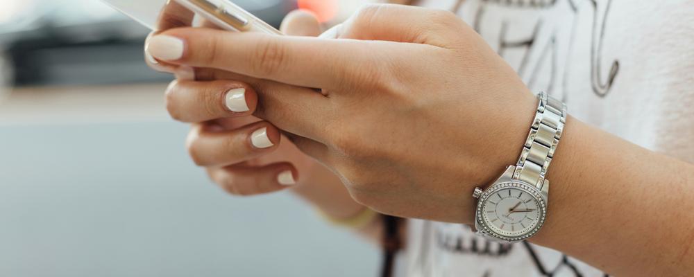 Händer som håller i mobiltelefon