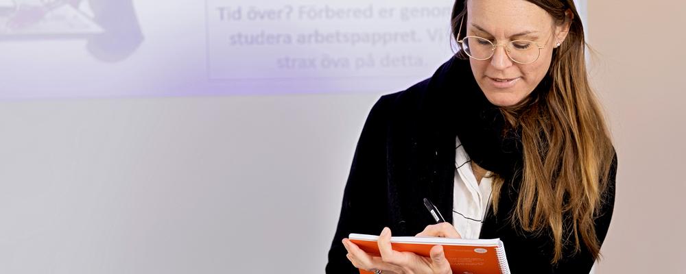Louise Holm skriver i anteckningsblock i klassrum