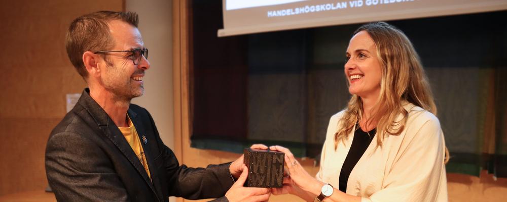 A woman presents an award to a man.