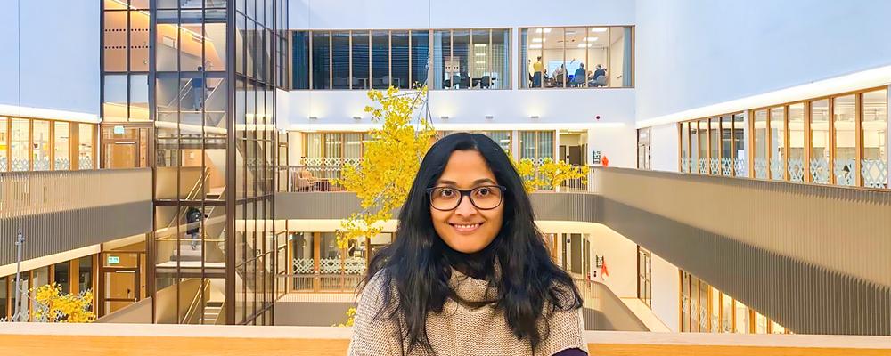 Kvinna med mörkt hår i ljusgård i modern byggnad.