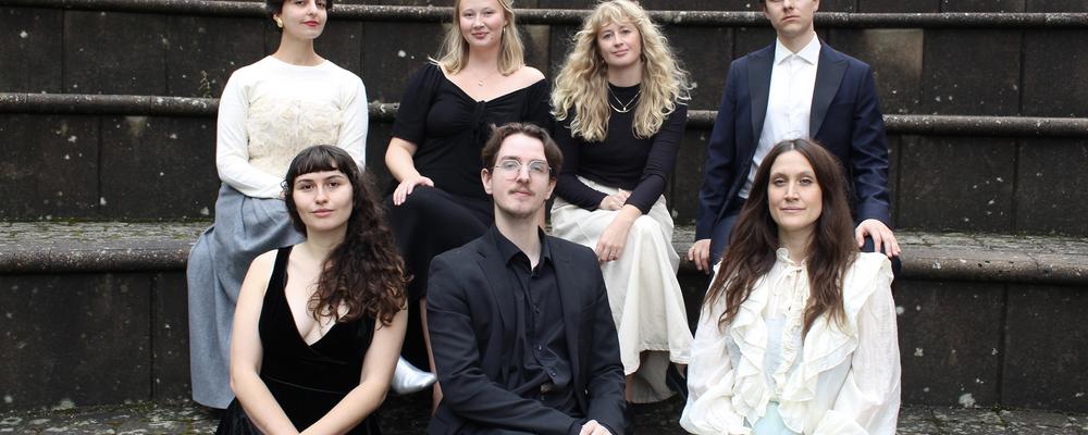 A group of people in front of a grey curtain
