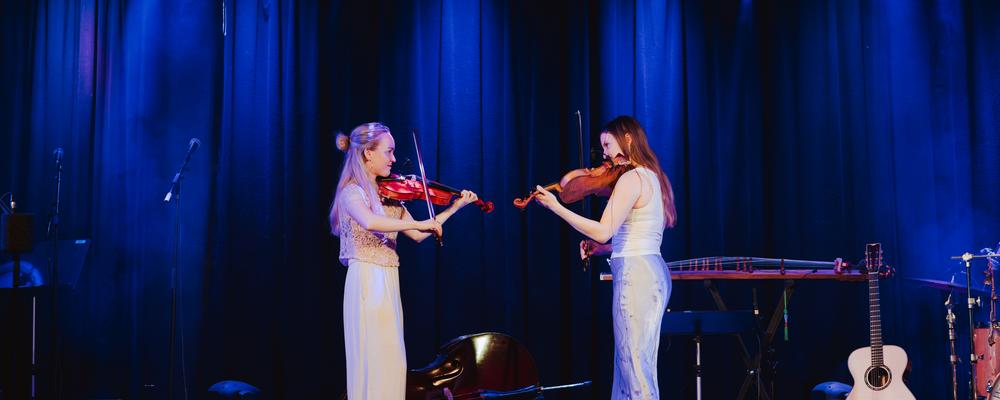Two persons playing violin on stage