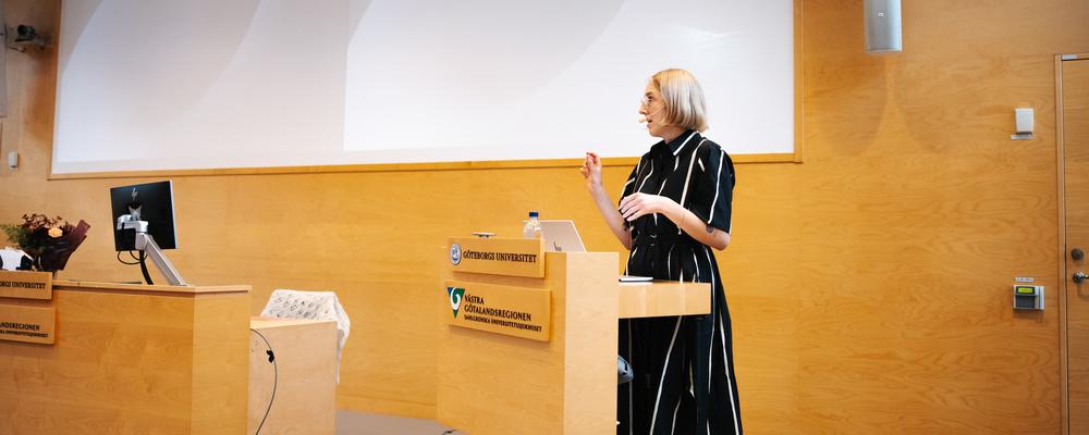 Blond kvinna presenterar inför publik