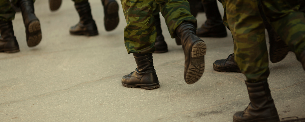 Foto av militäruniformsbeklädda ben som går i grupp